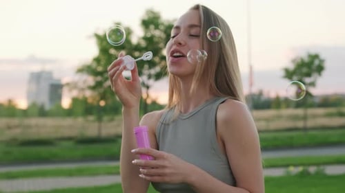 Smiling Woman Blowing Bubbles Outdoors at Sunset