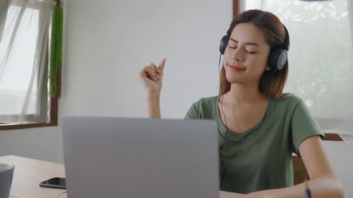 Woman Listening to Music Using Laptop at Home