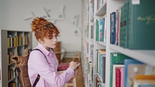 Redhead Girl Takes Books From Shelves in College Library