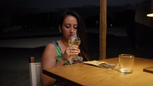 Woman Picking Up The Glass Of Wine And Drinking During Dinner At The Resort