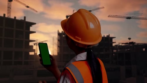 Back View Of Asian Female Engineer Working On A Green Screen Smartphone At Building Site