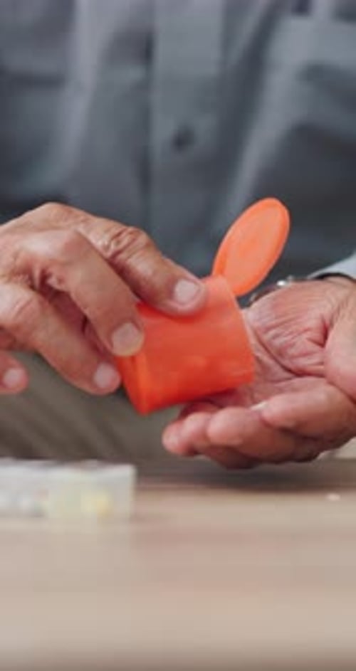 Mature Hands Dispensing Pills into Palm