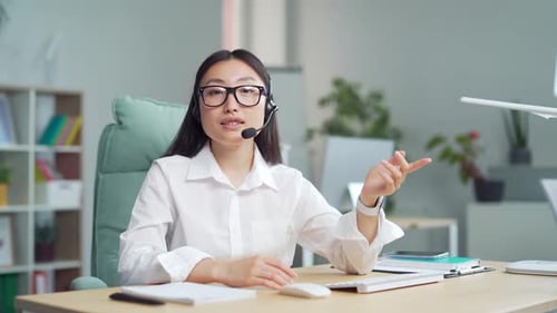 Young Adult Woman with Headset Speaking in Office