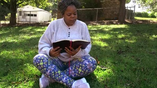Woman Reading Book Outside on Green Grass