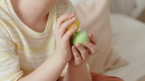 Child Holds Easter Eggs Indoors Close Up