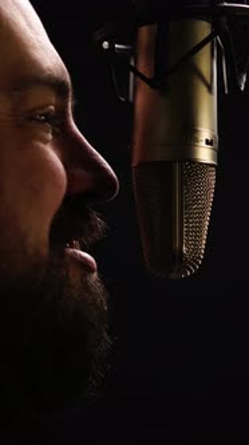 Vertical: Man With Beard Talking Closely to Professional Studio Microphone