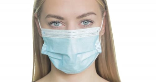 Close-up portrait of a blonde woman wearing medical PPE.