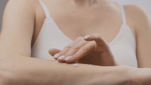 Woman Applies Lotion to Arm in Close Up