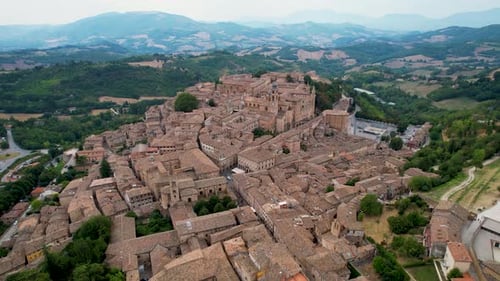 Panoramic aerial shot of Urbino, Italy, showcasing the town's historic brick buildings and winding s