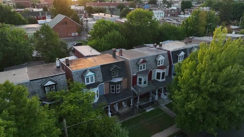 Warm summer golden hour light. Rising aerial reveals homes in downtown city in USA. Aerial establish