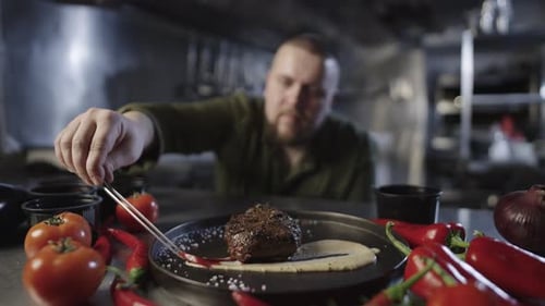 Chef Garnishes Steak in Restaurant Kitchen