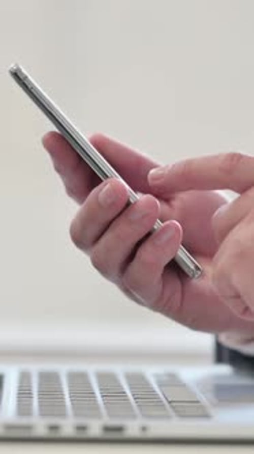 Vertical Video of Close up of Businessman with Laptop using Smartphone