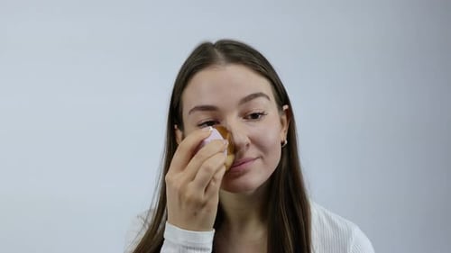 Woman Applying Makeup with Sponge for Beauty Routine