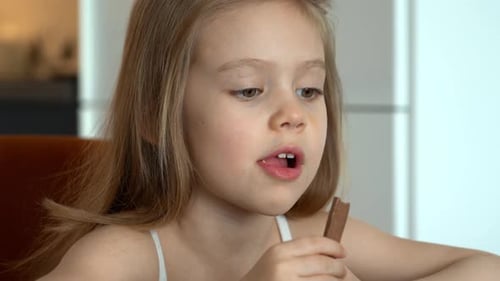 Girl Eats Chocolate at Home Child with Chocolate Candy Dessert Food Sweetness