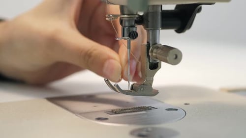 La costurera artesana llena el hilo en la bobina inferior de la máquina de coser automática