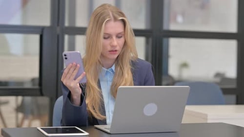 Businesswoman at Desk with Laptop and Smartphone