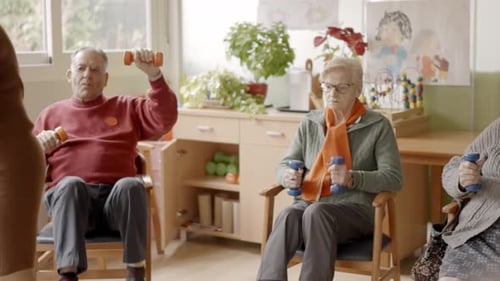 Seniors Exercising in a Nursing Home Using Pedals and Dumbbells