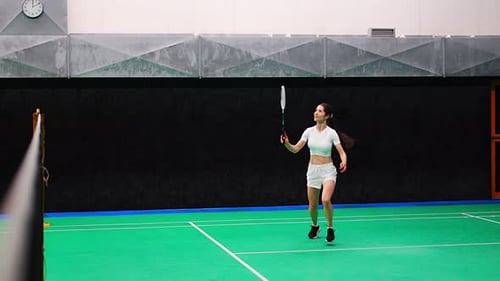 Sports Young Woman with Racket and Shuttlecock is Exercising Playing in Badminton on Inside Court