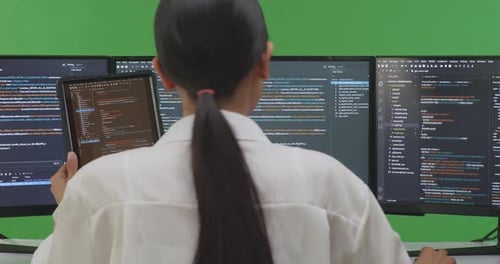 Asian Woman Developer Working With Tablet While Write Code With Multiple Screens In Green Screen
