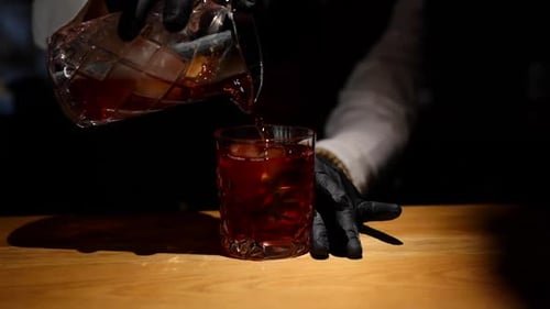 Bartender Pouring Drink into Glass with Ice