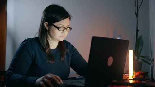 Woman working on laptop in dimly lit room