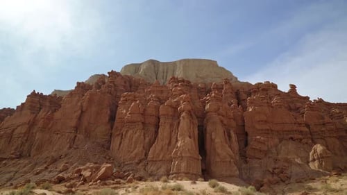 Tilt up shot revealing large red rock formations with a red and white rock butte on a hike inside of