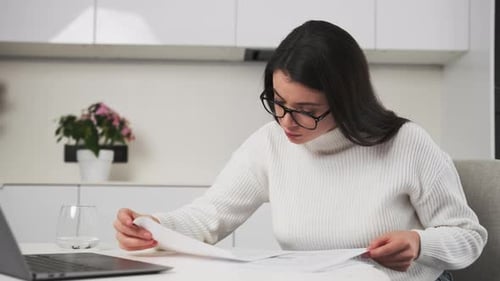 Accountant in Glasses Checks Documents Sitting at Table