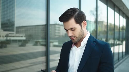 Close Up Confident Businessman Walking with Phone Outdoors. Serious Businessman Using Smartphone