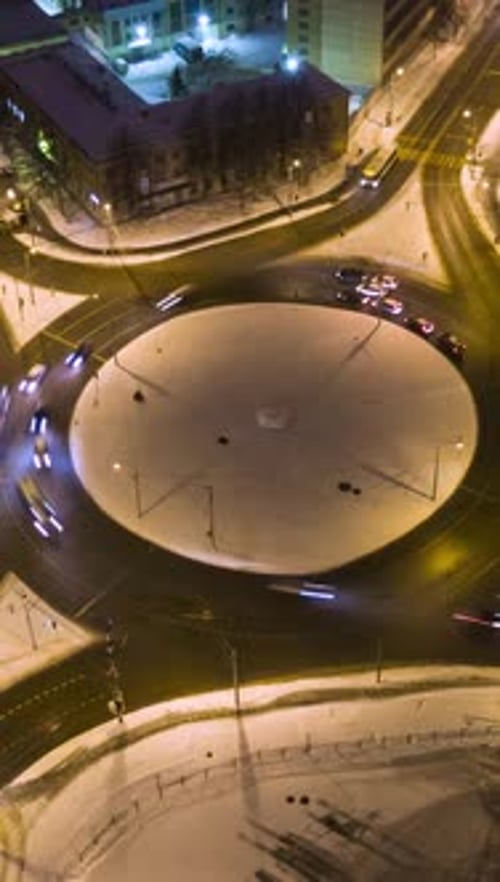 Illuminated Traffic Circle and Cars at Winter Night Round Crossroads Orbiting Aerial View Vertical