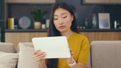 Woman Uses Tablet on Sofa at Home