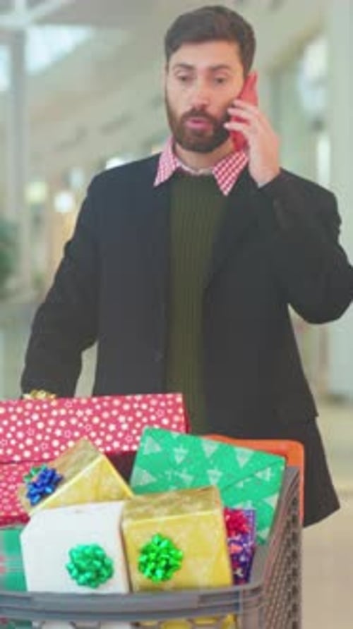 Store Visitor Clutches Wrapped Parcels While Urgently Speaking on Mobile During Seasonal Shopping