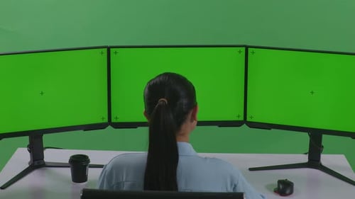 Back View Of Asian Woman Working With Mock Up Multiple Computer Monitor In Green Screen