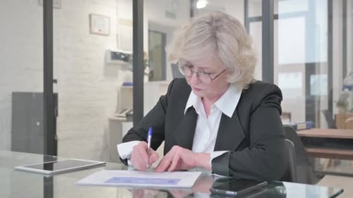 Businesswoman Writes on Document in Office
