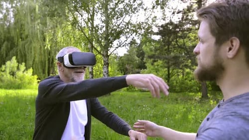 Young man enjoys virtual reality experience with his senior father in the park