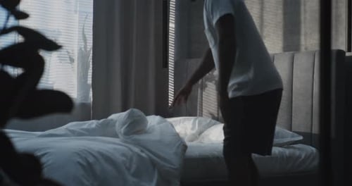 Man getting into bed to sleep in bedroom