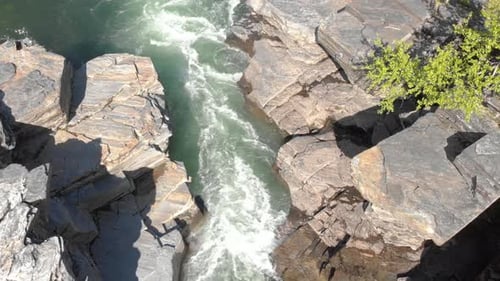 Wild river rapid flow through eroded Bedrock on a sunny day - Crane down shot