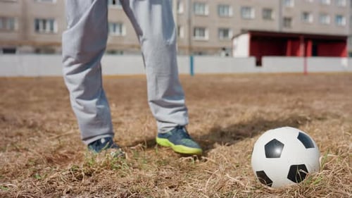 Legs Kick Soccer Ball on Dry Grass Field