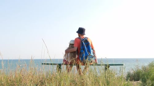 Happy father and daughter sitting on bench with marine landscape view. Dad and child having fun walk