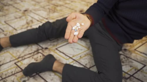 Person Lying Down with Handful of Pills