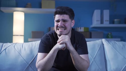 Young man with anxiety disorder crying thoughtfully.