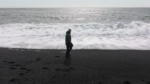 Man Running From Tide on Black Sand Beach