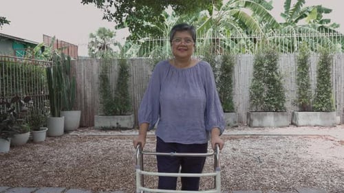 Senior Woman Using Walker in Yard Smiles