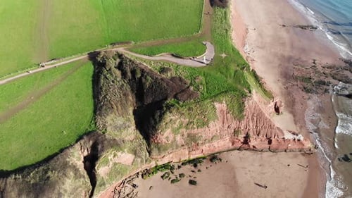 Aerial Over Orcombe Point Cliff Coastline In Exmouth With Visitors On Beach On Sunny Day. Pedestal U