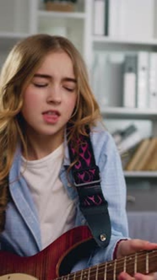 Teen Girl Energetically Plays Electric Guitar at Home