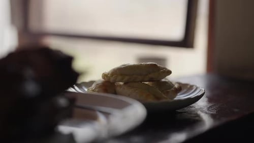 Gros plan d'empanadas argentines sur une assiette près d'une fenêtre