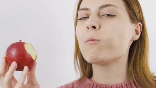 Close-up portrait of woman eating red apple. Eat fruit.