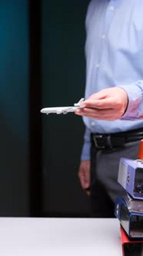 Vertical Video Businessman Holding Model Airplane in Office Setting