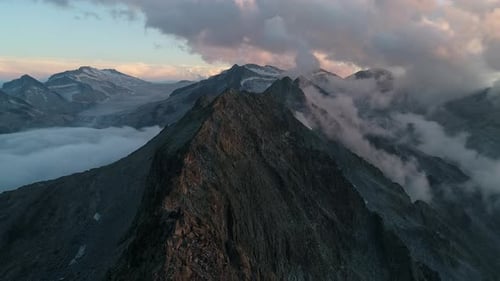 Picturesque view over rocky mountains peak at dusk. Flying over rugged alpine mountainous summits. D