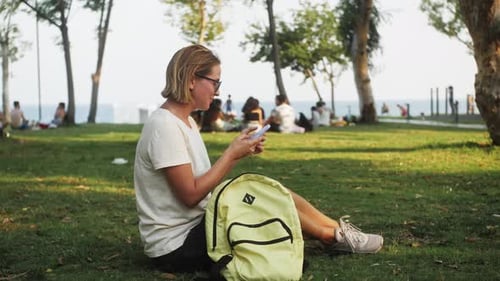 Smiling Young Woman Enjoys Using New Technology Smartphone on Sea Background