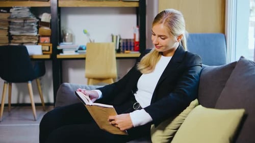 Young Woman Student or Businesswoman Reading a Book in the Library Students in a Good Mood Studying